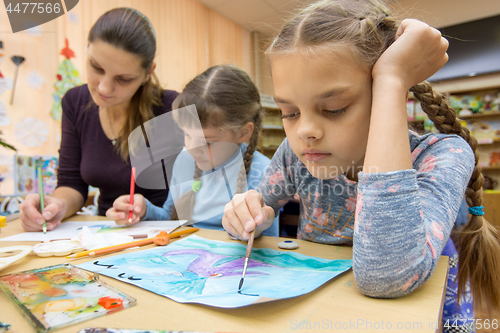 Image of The teacher helps the students in drawing class