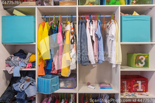 Image of Open wardrobe with things and toys in the children\'s room