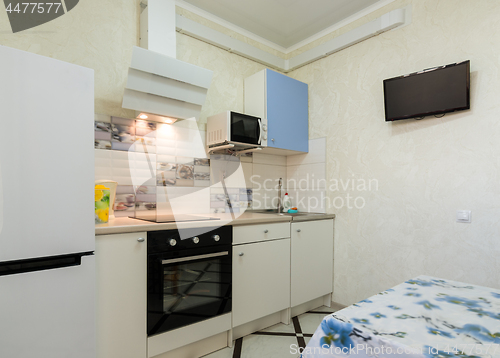 Image of The interior of a small kitchen with a TV on the wall