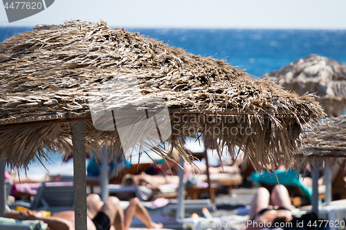 Image of beach with umbrellas and deck chairs by the sea in Santorini