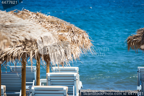 Image of beach with umbrellas and deck chairs by the sea in Santorini