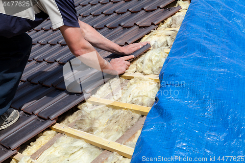 Image of a roofer laying tile on the roof