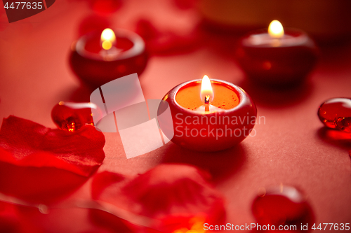 Image of Romantic dinner decoration. Red candles, flower petals, on the t