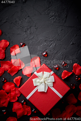 Image of Gift box on black stone table. Romantic holiday background with rose petals