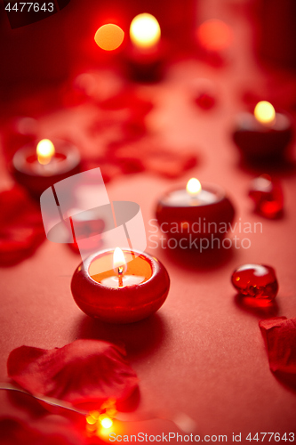 Image of Romantic dinner decoration. Red candles, flower petals, on the table