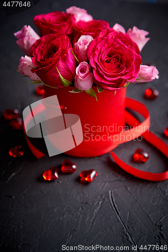 Image of Pink roses bouquet packed in red box and placed on black stone background