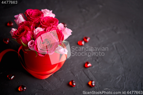 Image of Pink roses bouquet packed in red box and placed on black stone b