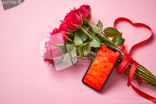 Image of Pink roses bouquet with hart shaped bow and mobile phone with copy space screen