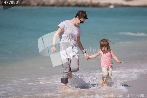 Image of mother and daughter running on the beach