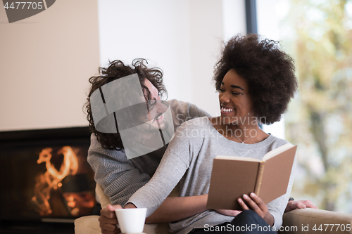 Image of multiethnic couple hugging in front of fireplace