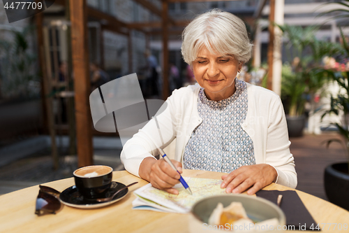 Image of senior woman with map and coffee at street cafe