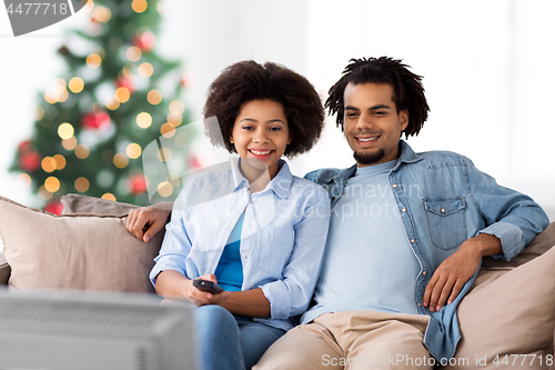 Image of happy couple watching tv at home on christmas