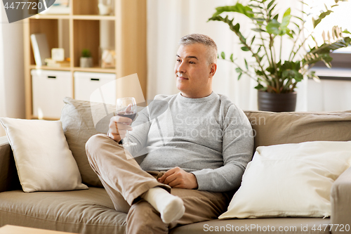 Image of man drinking red wine from glass at home