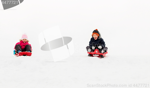 Image of kids sliding on sleds down snow hill in winter