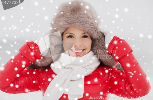 Image of happy smiling woman in winter fur hat outdoors