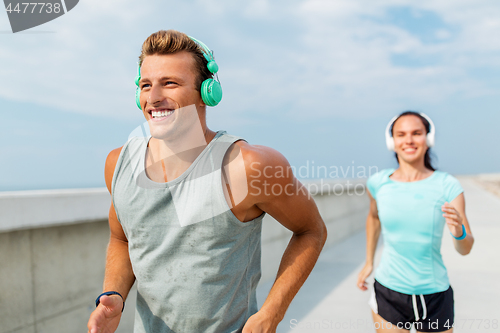 Image of couple with headphones running outdoors