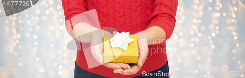Image of close up of woman in red sweater holding gift box