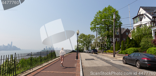 Image of Healthy lifestyle. Woman is jogging on Hamilton ave by Hamilton park, New Jersey. Manhattan of New York City in the background.