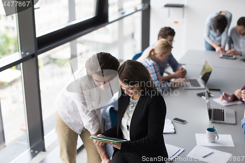 Image of Two Business People Working With Tablet in office