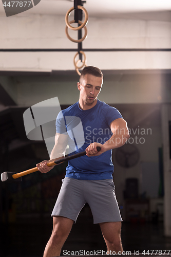 Image of man workout with hammer and tractor tire