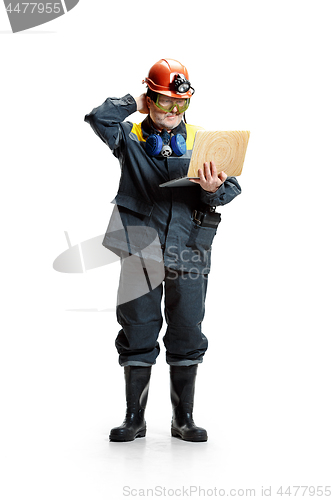 Image of The studio shot of pensive senior bearded male miner standing at the camera with laptop on a white background.