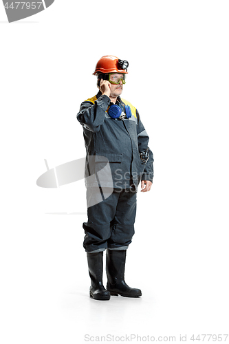 Image of The studio shot of serious senior bearded male miner standing in profile view at the camera with smartphone on a white background.