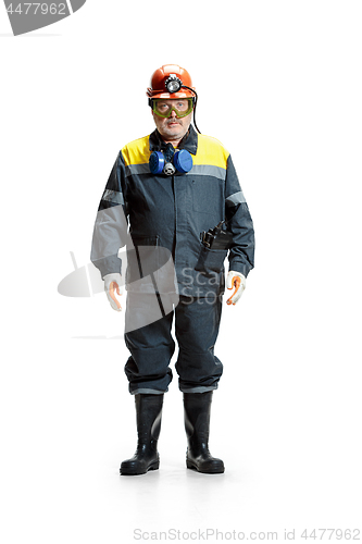 Image of The studio shot of serious senior bearded male miner standing at the camera on a white background.