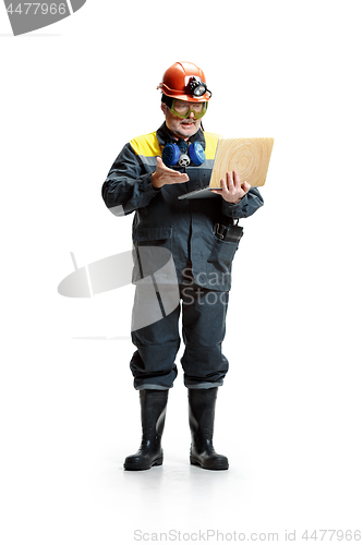 Image of The studio shot of serious senior bearded male miner standing at the camera with laptop on a white background.