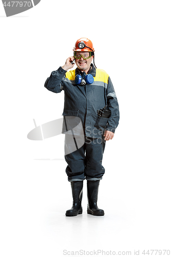 Image of The studio shot of happy senior bearded male miner standing at the camera with smartphone on a white background.