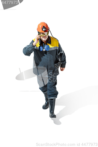 Image of The studio shot of senior bearded male miner standing at the camera on a white background.