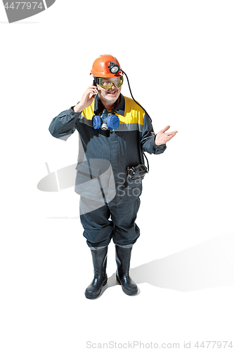 Image of The studio shot of senior bearded male miner standing at the camera on a white background.