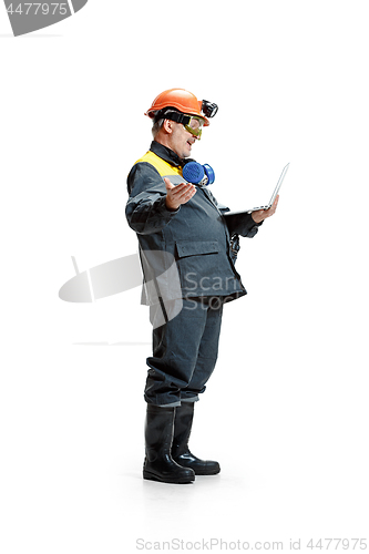 Image of The studio shot of happy senior bearded male miner standing in profile view at the camera with laptop on a white background.