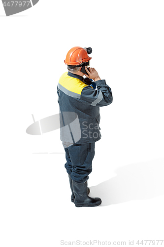 Image of The studio shot of senior bearded male miner standing at the camera on a white background.