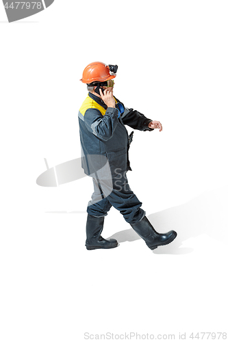 Image of The studio shot of senior bearded male miner standing at the camera on a white background.