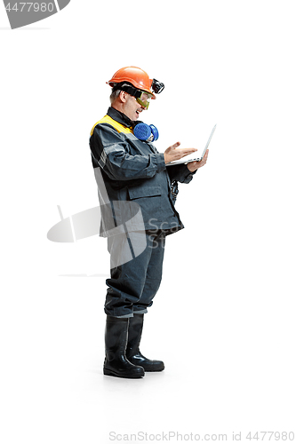 Image of The studio shot of happy senior bearded male miner standing in profile view at the camera with laptop on a white background.