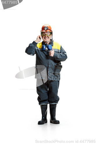 Image of The studio shot of happy senior bearded male miner standing at the camera with smartphone on a white background.