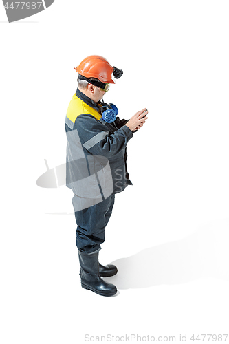 Image of The studio shot of senior bearded male miner standing at the camera on a white background.