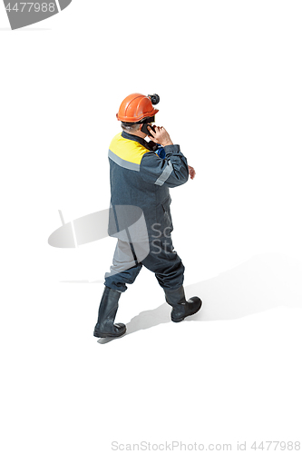 Image of The studio shot of senior bearded male miner standing at the camera on a white background.