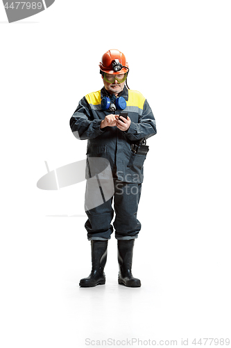 Image of The studio shot of serious senior bearded male miner standing at the camera with smartphone on a white background.