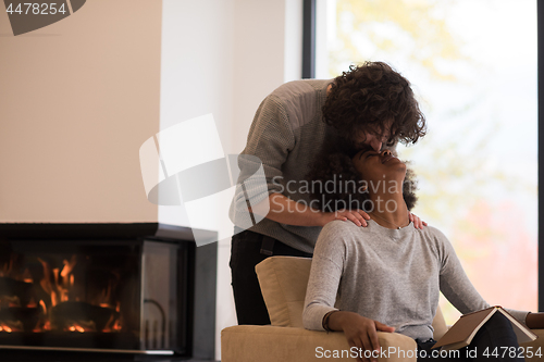 Image of multiethnic couple hugging in front of fireplace