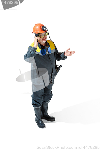 Image of The studio shot of senior bearded male miner standing at the camera on a white background.