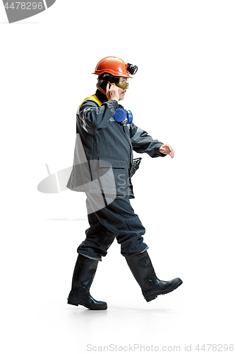 Image of The studio shot of serious senior bearded male miner in motion at the camera with smartphone on a white background.