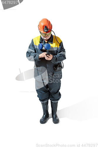 Image of The studio shot of senior bearded male miner standing at the camera on a white background.