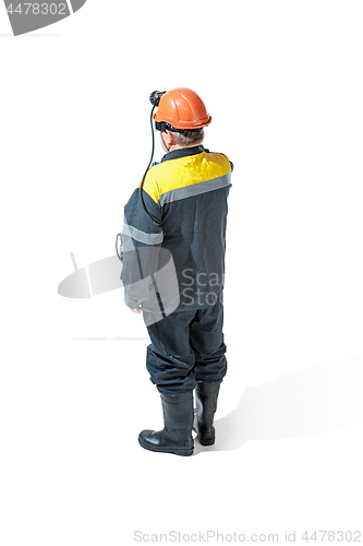 Image of The studio shot of senior bearded male miner standing at the camera on a white background.