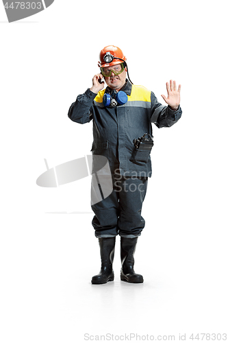 Image of The studio shot of disgusted senior bearded male miner standing at the camera with smartphone on a white background.