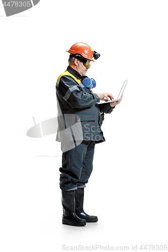 Image of The studio shot of serious senior bearded male miner standing in profile view at the camera with laptop on a white background.