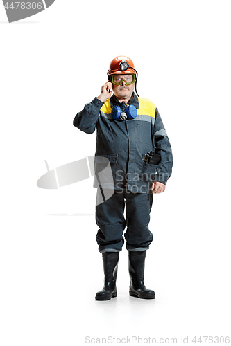 Image of The studio shot of serious senior bearded male miner standing at the camera with smartphone on a white background.