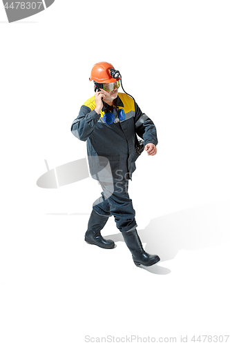 Image of The studio shot of senior bearded male miner standing at the camera on a white background.