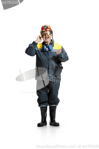 Image of The studio shot of happy senior bearded male miner standing at the camera with smartphone on a white background.