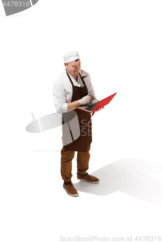 Image of Serious butcher posing with a laptop isolated on white background